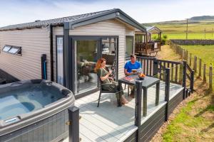 two people sitting on the deck of a tiny house at Machrihanish Holiday Park in Campbeltown