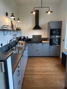 a kitchen with stainless steel appliances and wooden floors at Le Haut 33 : Maison bourgeoise de caractère à Laon in Laon