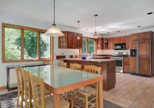 una cucina con tavolo in vetro e armadi in legno di Wonderful 6 Bedroom Home At Hamptons a Noyack