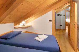 a bedroom with a blue bed and wooden ceilings at Casa Francesca Lidia in Bormio