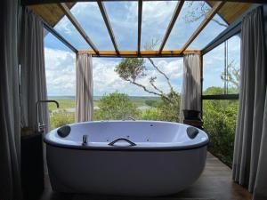 a bath tub in a room with a large window at Morada Alto Das Nuvens in São José dos Ausentes +15 photos