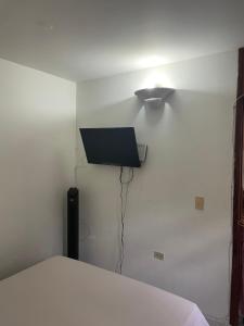 Habitación con cama y TV en la pared. en Casa de Descanso Marrón 101, en Villavicencio