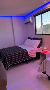 1 dormitorio con 1 cama en una habitación con luces violetas en AP studio805, en Maceió