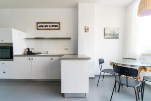 uma cozinha com armários brancos e uma mesa e cadeiras em Ziv Apartments - Hayarkon 196 em Tel Aviv