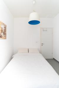 un letto bianco in una camera bianca con luce blu di Ziv Apartments - Hayarkon 196 a Tel Aviv