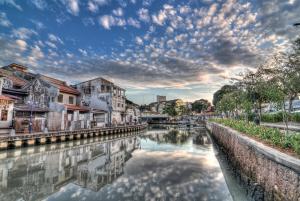 a river in a city with buildings and a cloudy sky at Pax 6+3 Grand Lux Melaka homestay in Melaka