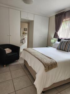 a bedroom with a large bed and a black chair at Little Greece in Cape Town