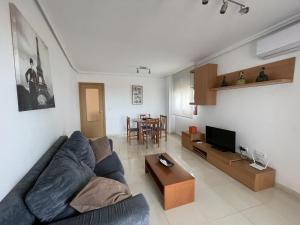 ein Wohnzimmer mit einem Sofa, einem TV und einem Tisch in der Unterkunft Bertur Mira d'Or-57 in Peñíscola