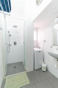 een witte badkamer met een douche en een wastafel bij Ziv Apartments - Hayarkon 196 in Tel Aviv
