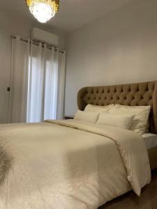 um quarto com uma grande cama branca e um lustre em October Luxury Apartments em Ioannina