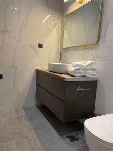 een badkamer met een wastafel, een toilet en een spiegel bij October Luxury Apartments in Ioannina