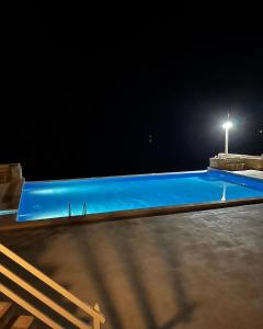 a blue swimming pool at night with a street light at Villa GÊMEO vue mer, piscine accès privé plage in Calheta Do Maio