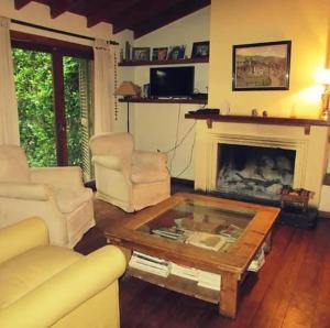 sala de estar con chimenea, 2 sillas y mesa de centro en Amplia casa con parque y pileta en Olavarría