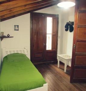 1 dormitorio con cama verde y puerta de madera en Amplia casa con parque y pileta en Olavarría