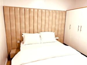 a bedroom with a large bed with a wooden headboard at 1-bedroom apartment at Asokoro by ECOWAS in Abuja