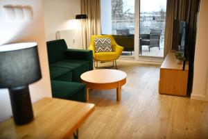 NADMORSKIE TARASY PORT -NAVIGATOR في كولوبرزيغ: غرفة معيشة مع أريكة خضراء وكرسي اصفر