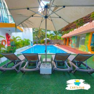 eine Gruppe von Stühlen und einem Sonnenschirm neben einem Pool in der Unterkunft The Cantamar Beach Hostel in Santa Marta