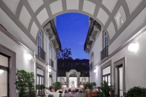ナポリにあるHotel Piazza Bellini & Apartmentsの中庭に座る人々の入った建物のアーチ道