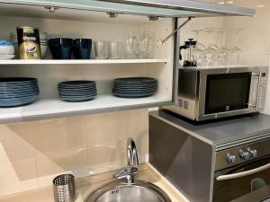 a kitchen with a sink and a microwave and plates at Beautiful Bright Loft in San Sebastián de los Reyes