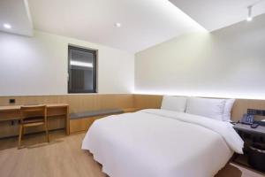 a bedroom with a large white bed and a desk at Hotel TARA in Seoul