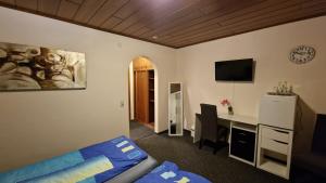 Schlafzimmer mit einem Bett und einem Schreibtisch mit einem TV in der Unterkunft Hotel & Restaurant - Zum Schleicher Kuckuck in Schleich