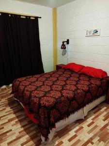 1 dormitorio con 1 cama con edredón rojo en Cabaña Buenos Recuerdos II en Villa Santa Cruz del Lago