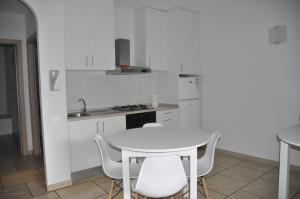 a white kitchen with a white table and chairs at Apartamento Moradias Djadsal próximo à Praia de Santa Maria in Espargos