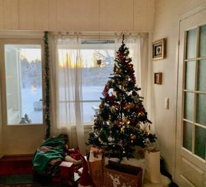 a christmas tree in a room with a window at Riverside Home near Santa Claus Village - beautiful house in a prime location in Rovaniemi
