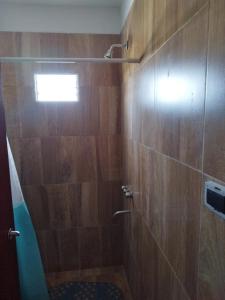 y baño con ducha y paredes de madera. en Cabaña Buenos Recuerdos II en Villa Santa Cruz del Lago