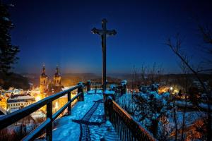 a cross on a snowy hill with a city in the background at Ferienhaus Sylvia beim Waldrand in Gößweinstein