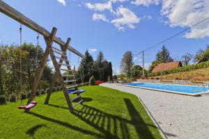 a playground with a wooden swing and a swimming pool at Holiday Home Grga-Three Bedroom House with Swimming Pool in Gornja Voća