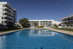 a large swimming pool in front of a building at Hopstays - Vilamoura Aldeia do Mar in Quarteira