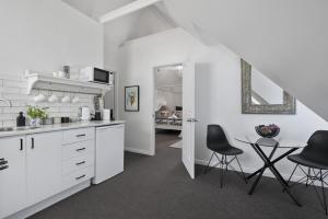 a white kitchen with black chairs and a table at Bella Abode on Bribie - Loft with Pool in Bongaree