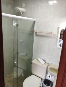 a bathroom with a toilet and a glass shower at Andorinhas Suites in Búzios