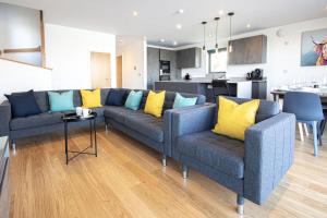 a living room with two blue couches and a kitchen at Minety Lake 43, Green Haven in Somerford Keynes