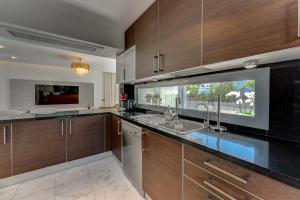 a kitchen with wooden cabinets and a large window at El Duque Private Lux Villa in Adeje