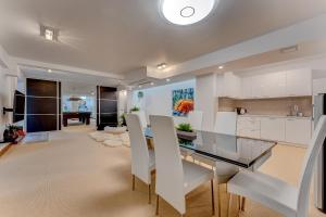 a kitchen with white cabinets and a dining table and chairs at El Duque Private Lux Villa in Adeje