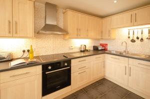 a kitchen with white cabinets and a black appliance at The Stables, Elterwater in Elterwater