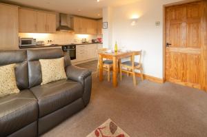 a living room with a leather couch and a table at The Stables, Elterwater in Elterwater