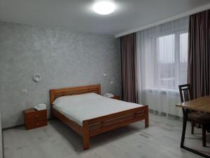 a bedroom with a bed and a table and a window at Perfecthotel in Myrhorod