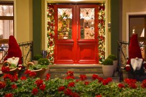 a red front door with christmas decorations and flowers at Hotel Bertoluci in Gramado