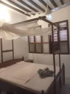 a bedroom with a bed with a canopy and windows at Iddi House in Jambiani