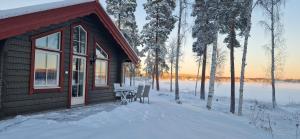 a cabin with a table and chairs in the snow at Lakeside log cabin Främby Udde Falun in Falun