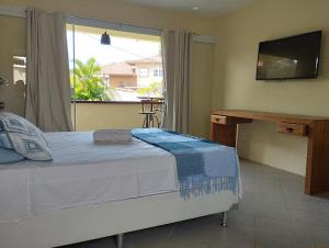 sypialnia z łóżkiem, biurkiem i oknem w obiekcie Andorinhas Suites w mieście Búzios