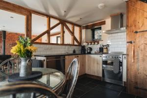 a kitchen with a glass table and a stove at Swallows Nest at Widemouth Bay - 2 bedroom cottage both rooms twin or king in Bude