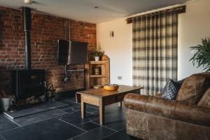 a living room with a couch and a fireplace at Swallows Nest at Widemouth Bay - 2 bedroom cottage both rooms twin or king in Bude