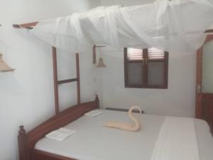 una camera con due letti con lenzuola bianche di Iddi House a Jambiani
