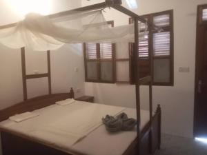 1 dormitorio con 1 cama con dosel y ventanas en Iddi House en Jambiani