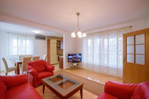 Kuća- VILLA EVA في Široki Brijeg: غرفة معيشة مع أريكة حمراء وطاولة