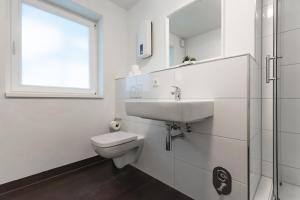 uma casa de banho branca com um lavatório e um WC em T&K Apartments - Several Apartments in Wegberg em Wegberg